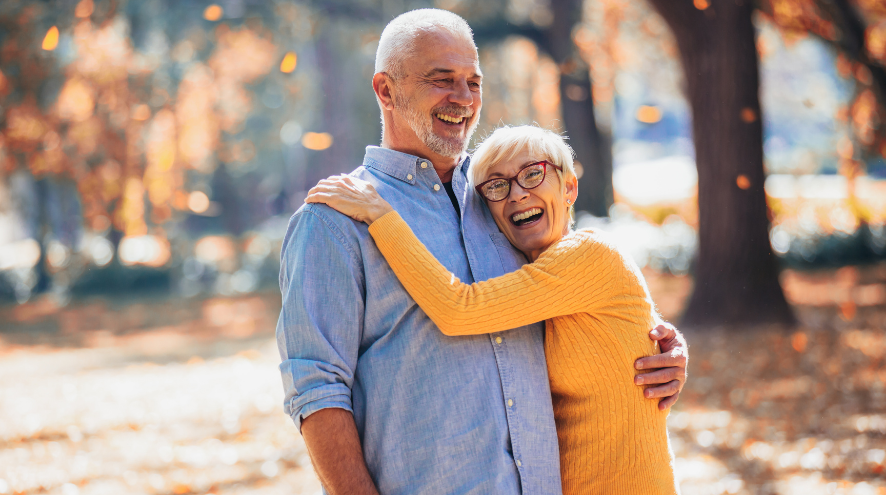 couple standing and smiling among fall leaves