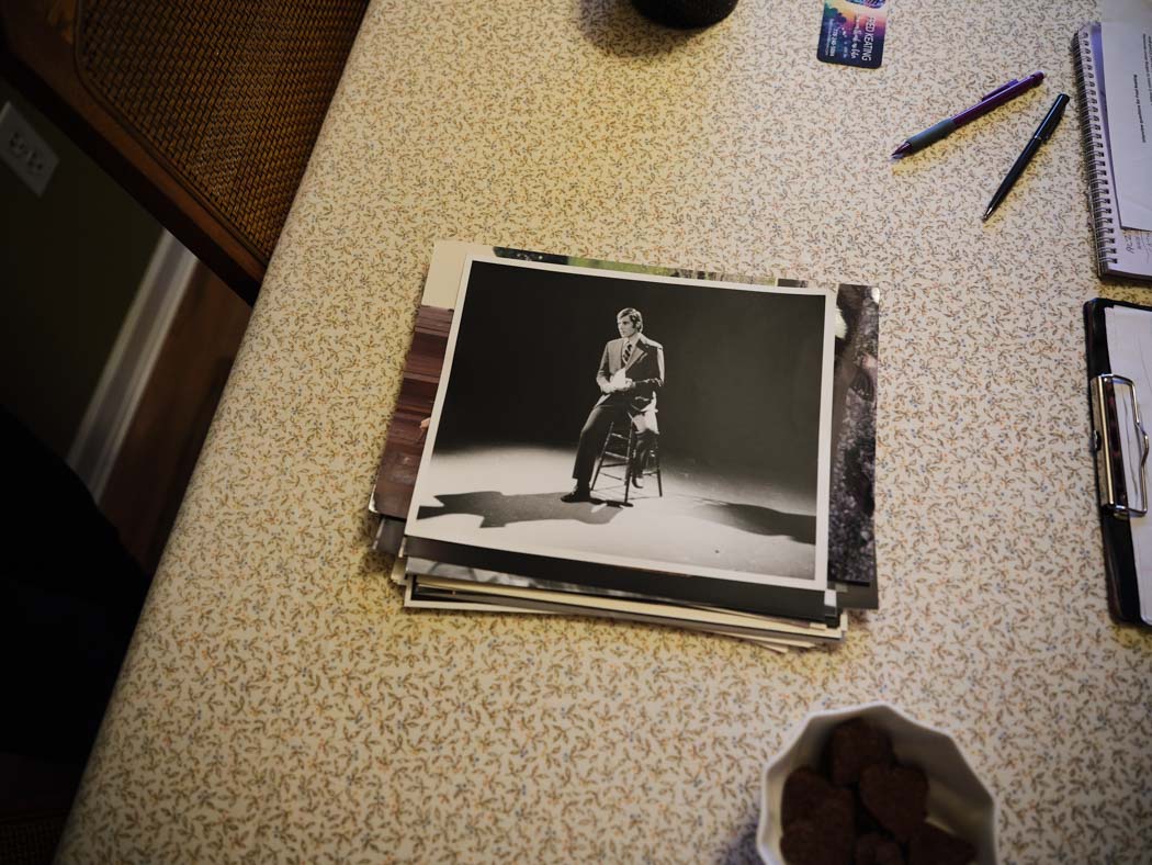 A stack of black-and-white photographs rests on a tabletop, with a portrait visible on top.