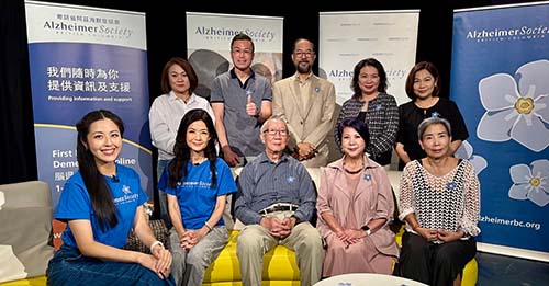 A large group of people sit together in front of pop-up banners.