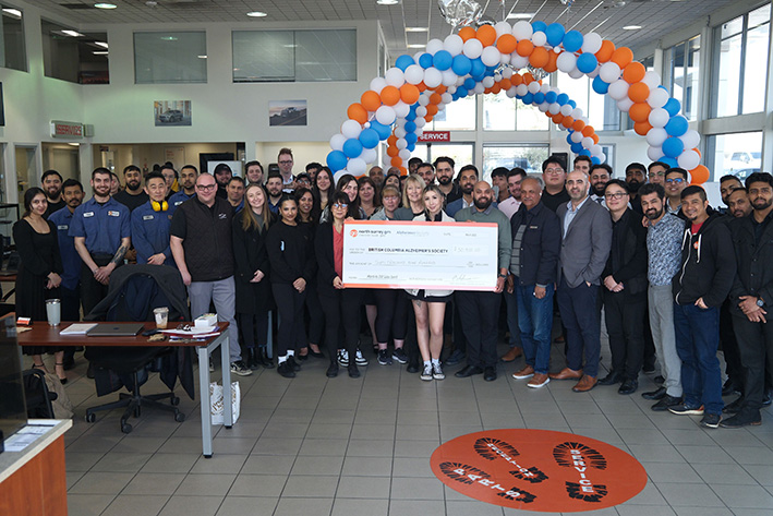 A large group of Go Auto employees within one of their dealerships poses with an oversized cheque made out to the Alzheimer Society of B.C.