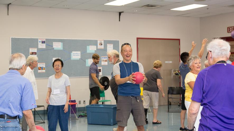 A volunteer at a Minds in Motion session, smiling and throwing a ball.
