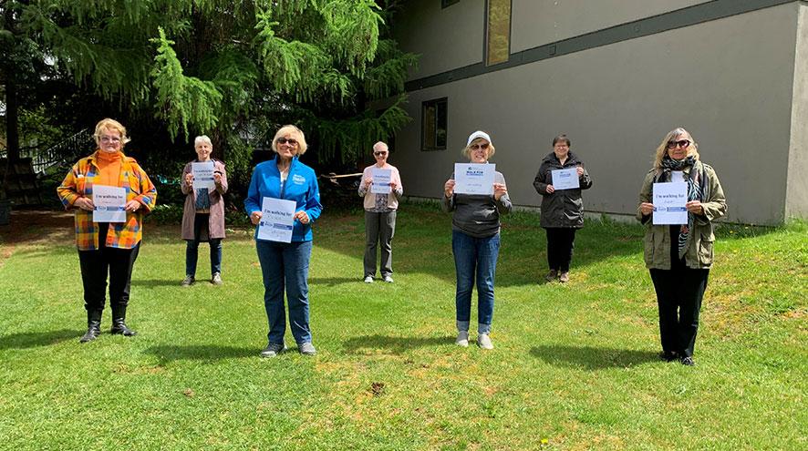 Seven volunteers of the IG Wealth Management Walk for Alzheimer's holding signs in support of the event in a social distanced formation