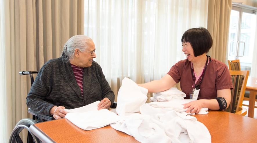 Health-care worker and senior sitting and interacting at a table