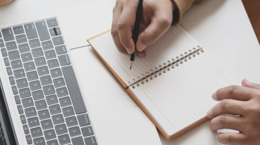 Person working on a laptop and taking notes 