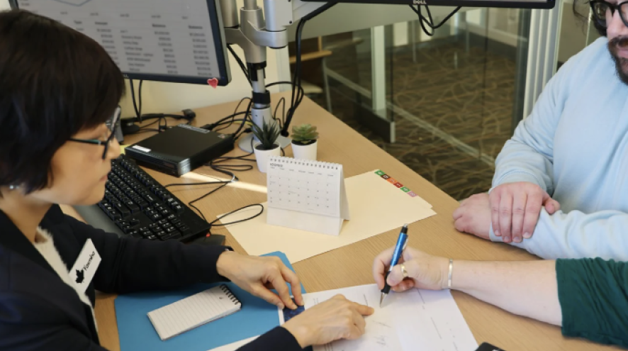 Bank employee pointing at a document for a client to sign