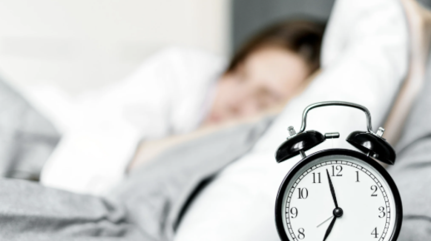 Image of person sleeping next to an alarm clock