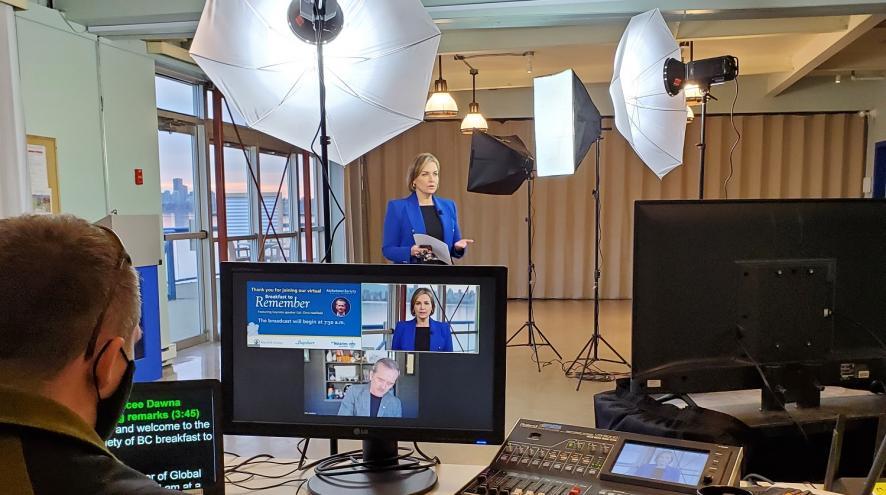 A woman in a recording studio is speaking to the camera while a producer at a computer looks on.