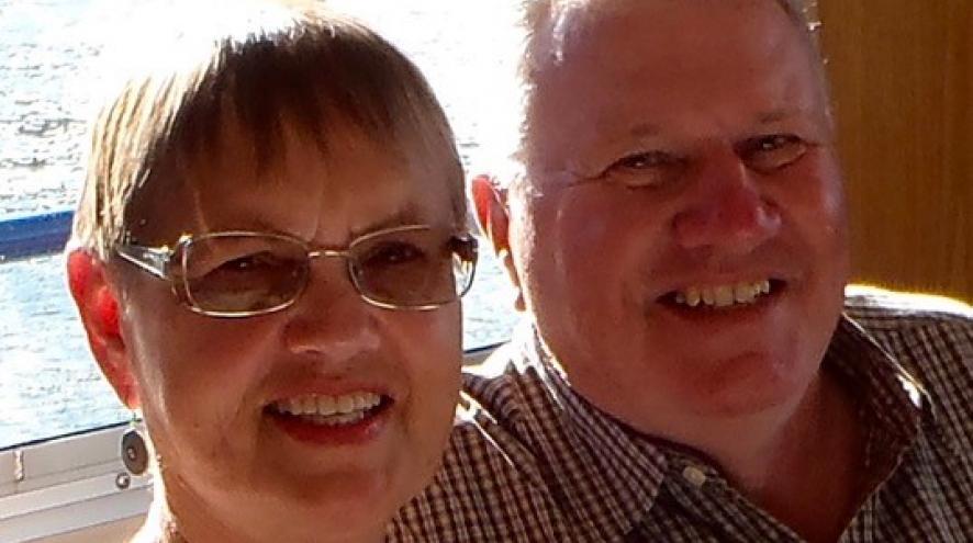 An older couple sitting next to each other, smiling.