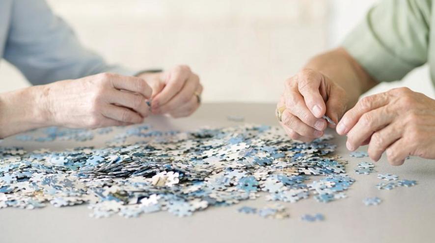A closeup of two sets of hands working on a puzzle