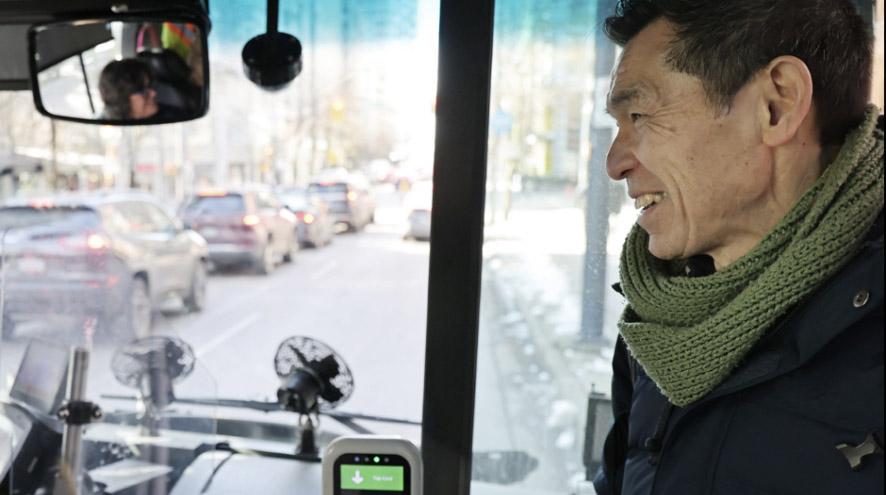 A man smiles at the driver as he boards a bus.