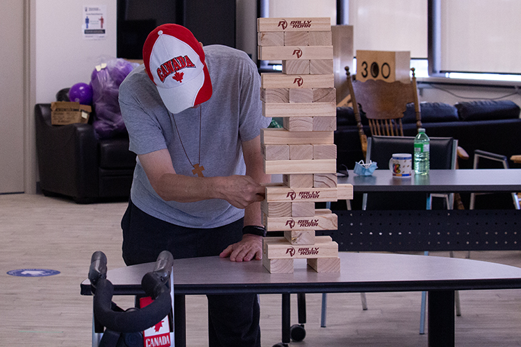 man with red and white Canada hat playing a game of giant Jenga