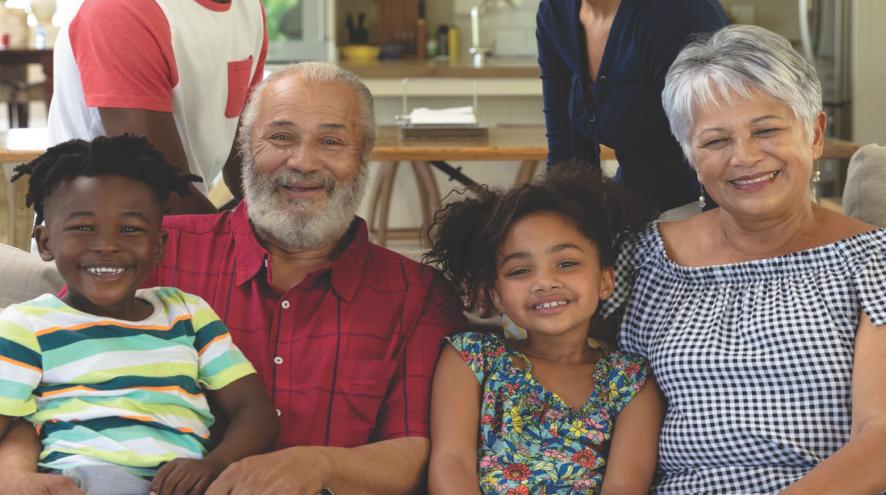 Multi-racial and multi-generational family smiling and sitting on a couch