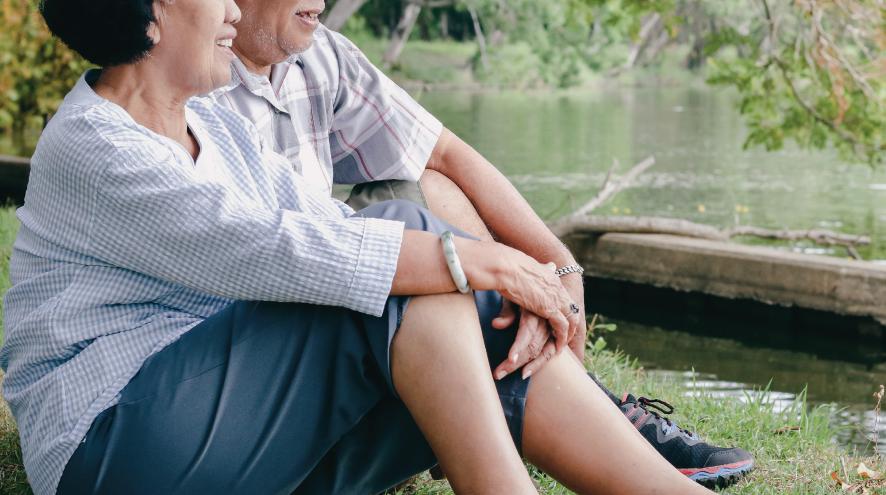 Smiling older couple sitting by a pond