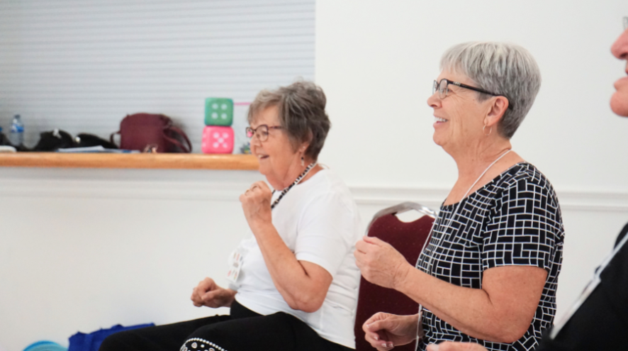 Two individuals sitting and dancing with their hands facing left.