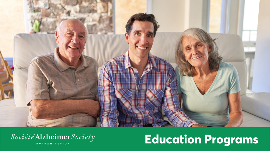 A man sitting on the couch with his parents on either side smiling at the camera.