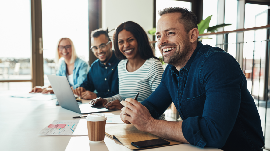 Individuals sitting in a meeting room and smiling.