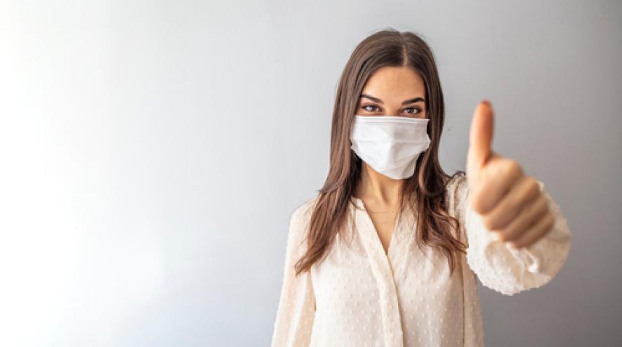 masked woman giving thumbs up