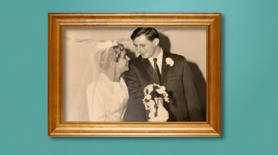 A photo of Maggie and Don on their wedding day in a wooden frame, hanging on a teal wall.