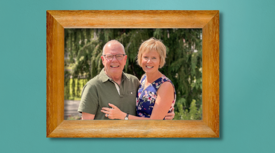 A photo of Peggy and her husband, Eric, in a wooden photo frame hanging on a teal wall