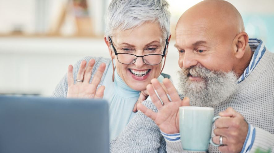 Man and woman using video chat on computer while drinking coffee