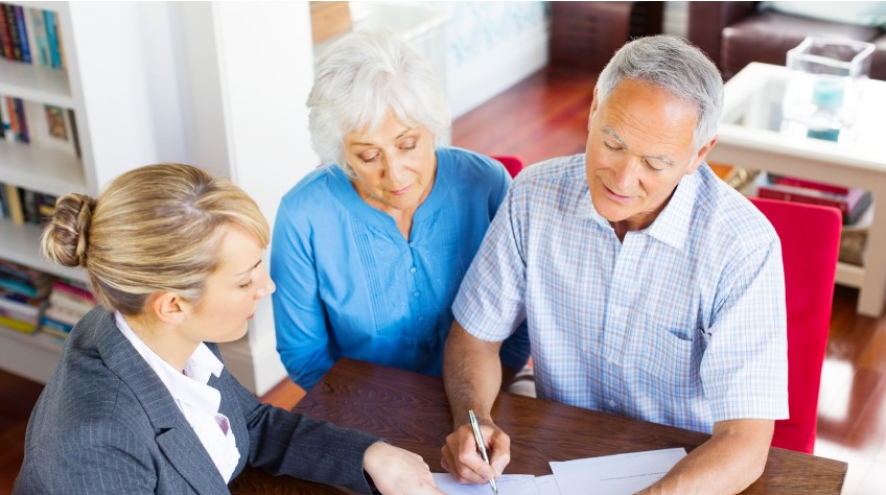 Senior couple filling out a form with an advisor.