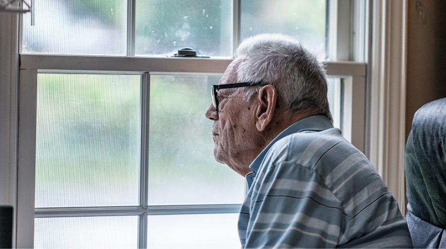 An older man staring out through a window