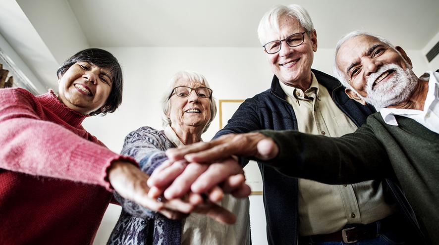 Group of senior friends with their hands in a circle.