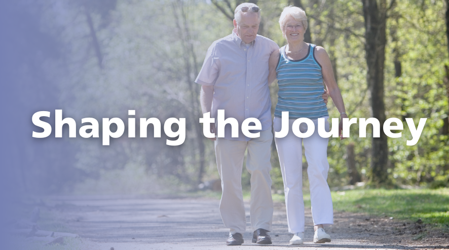 Two older people walk arm in arm together on a trail in a forest. The overset text reads "Shaping the Journey."