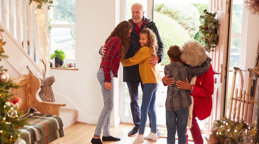 Excited Grandchildren Greeting Grandparents With Presents Visiting During Holidays