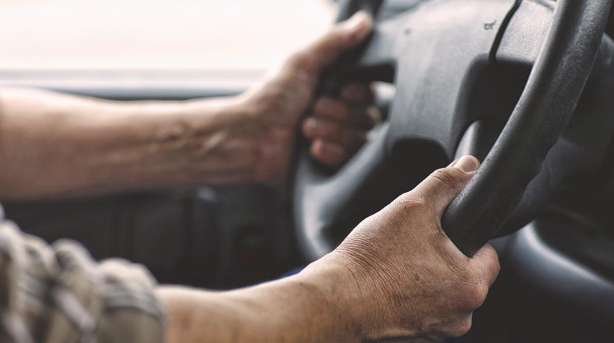 An image of a person's hands holding onto a steering wheel in a car.