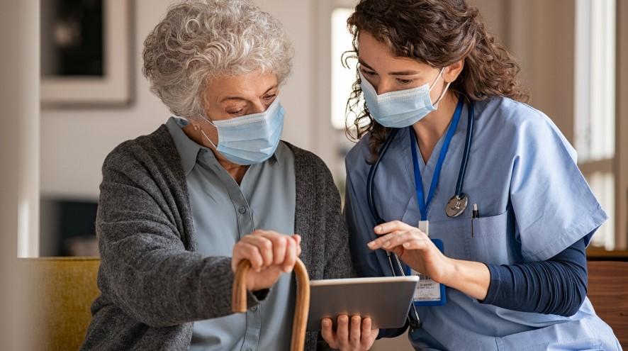 Healthcare provider showing a senior woman in her care something on her tablet.