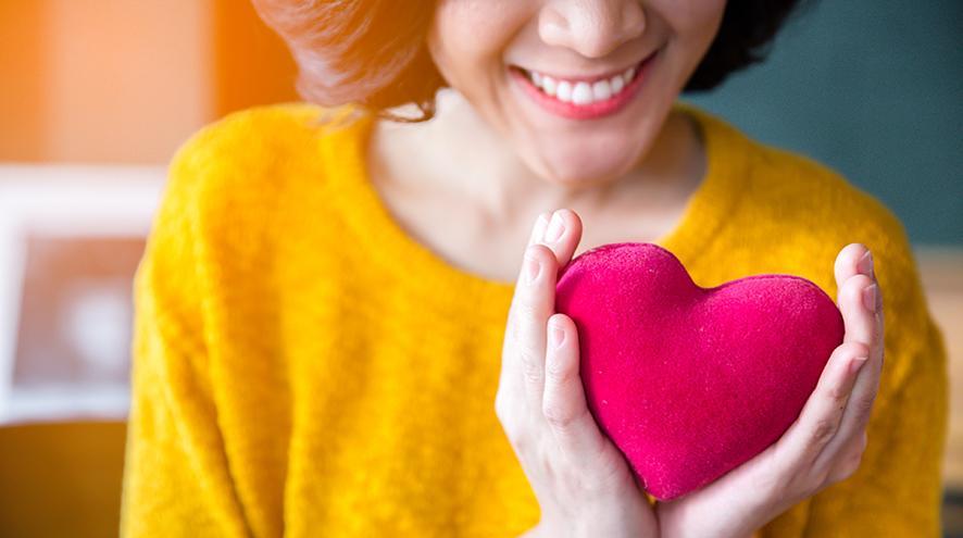 Young woman holding a plush toy heart.
