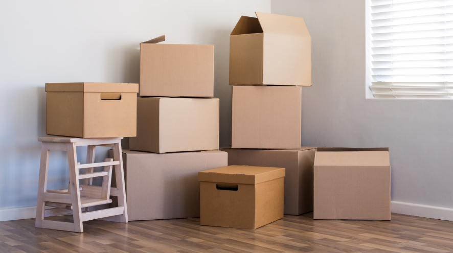 Stack of cardboard boxes beside a window.