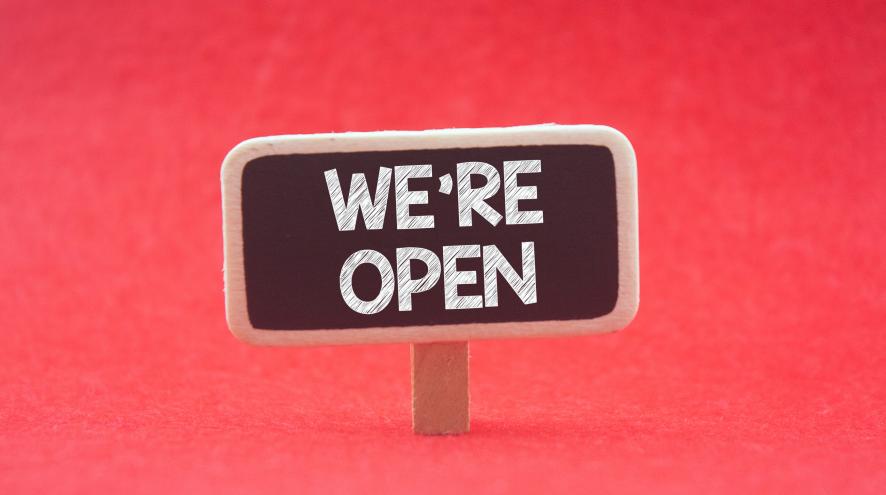 Small chalkboard sign on a red background, reading "we're open" in capital white letters.
