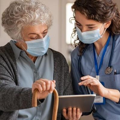 Healthcare-provider-shows-senior-woman-something-on-her-tablet