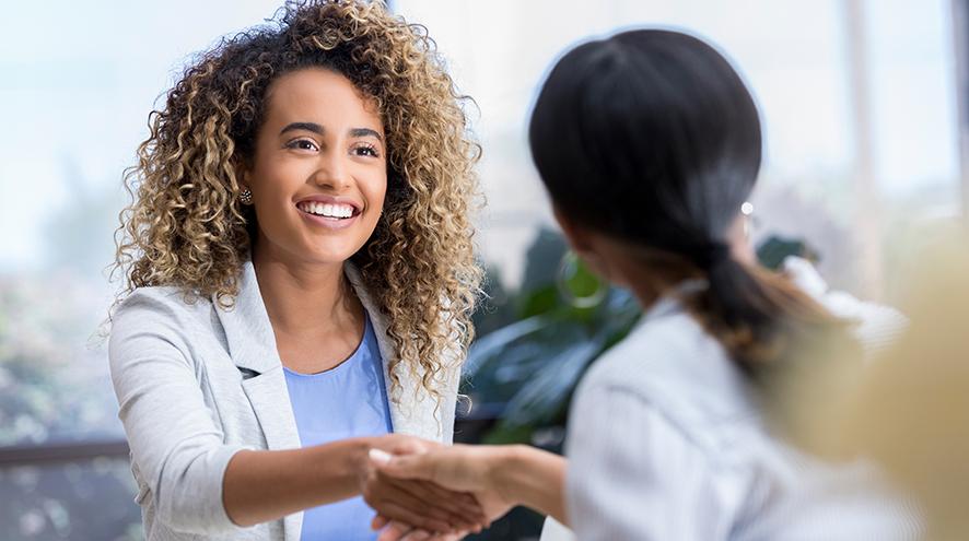 Young businesswoman greets colleague.