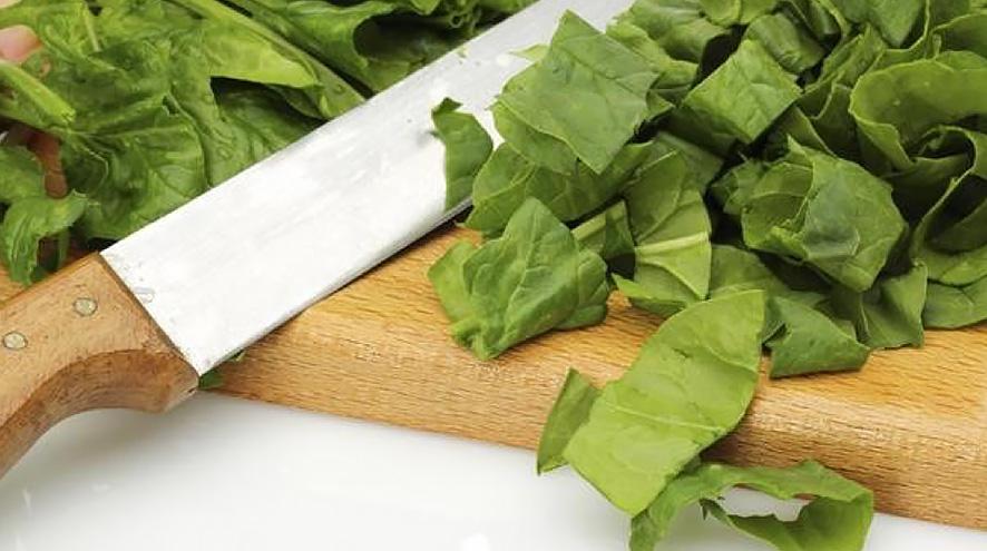 Chopped spinach with kitchen knife on cutting board