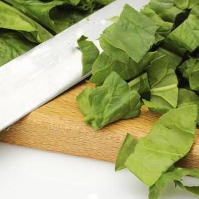 Chopped spinach with kitchen knife on cutting board