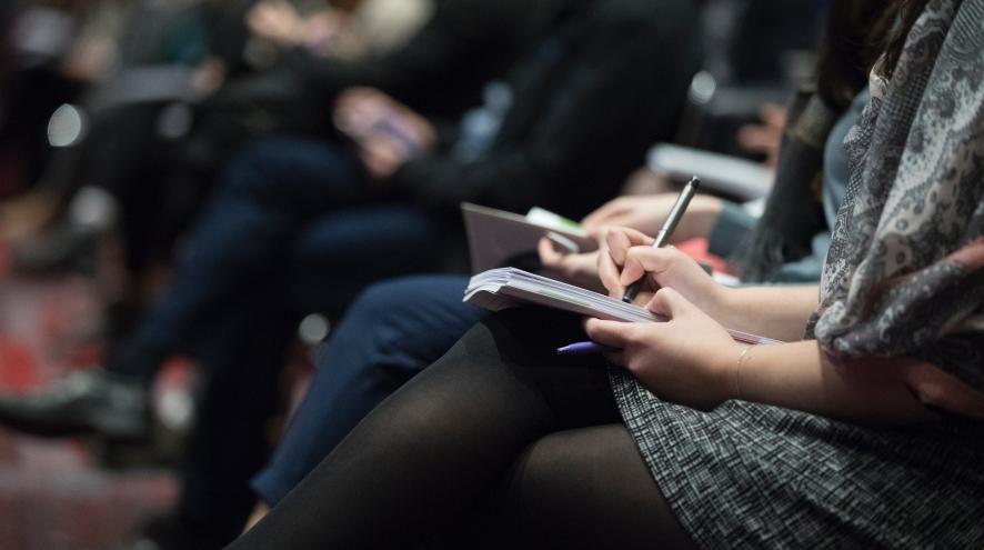 people sitting in a forum taking notes