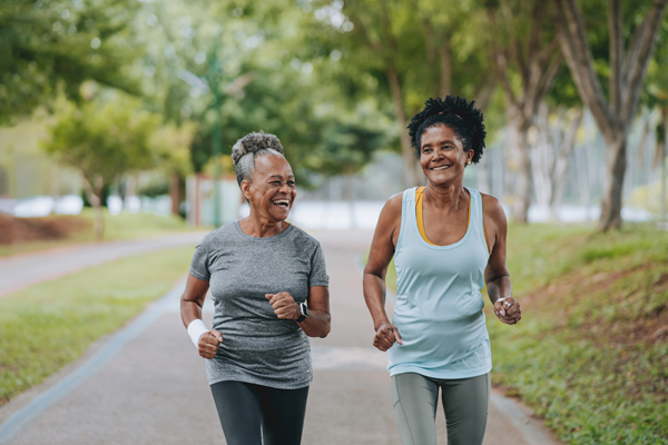 Two women running outdoors and smiling