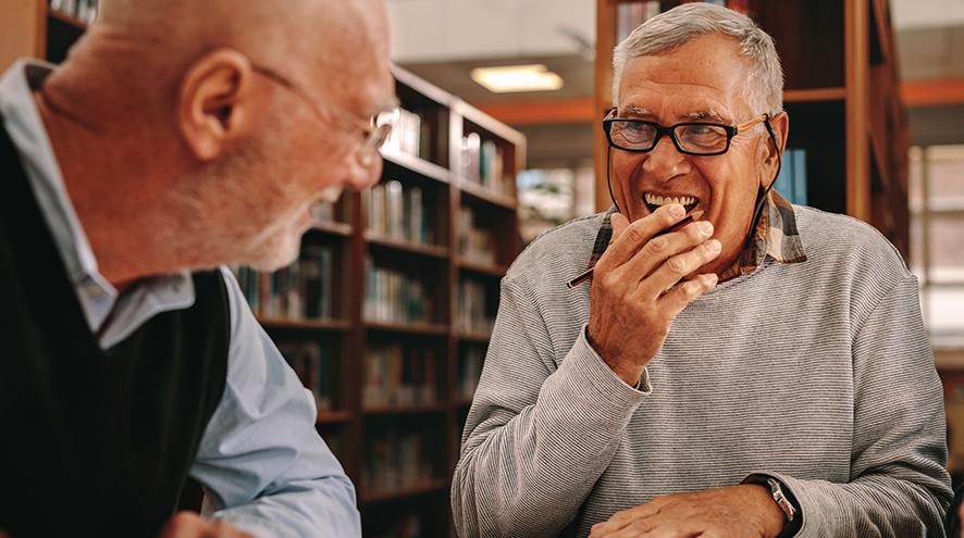 Two seniors in a library.