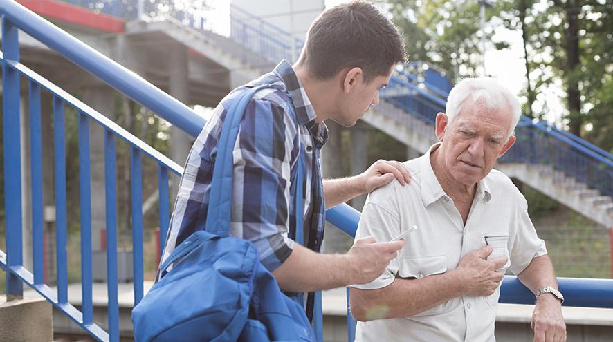 Young man helping senior man under distress.