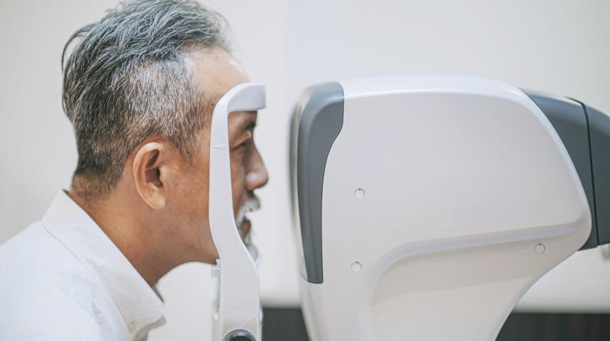 Senior man peering into eye-testing device.