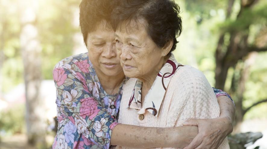 Senior woman hugging her family member in the park during a sunny day.