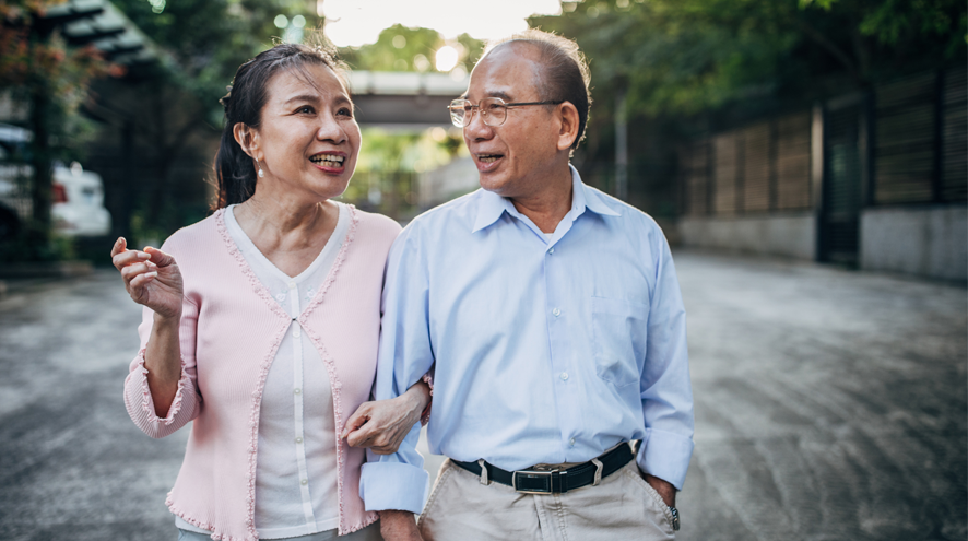 Midlife man and woman walk arm in arm in an outdoor public space