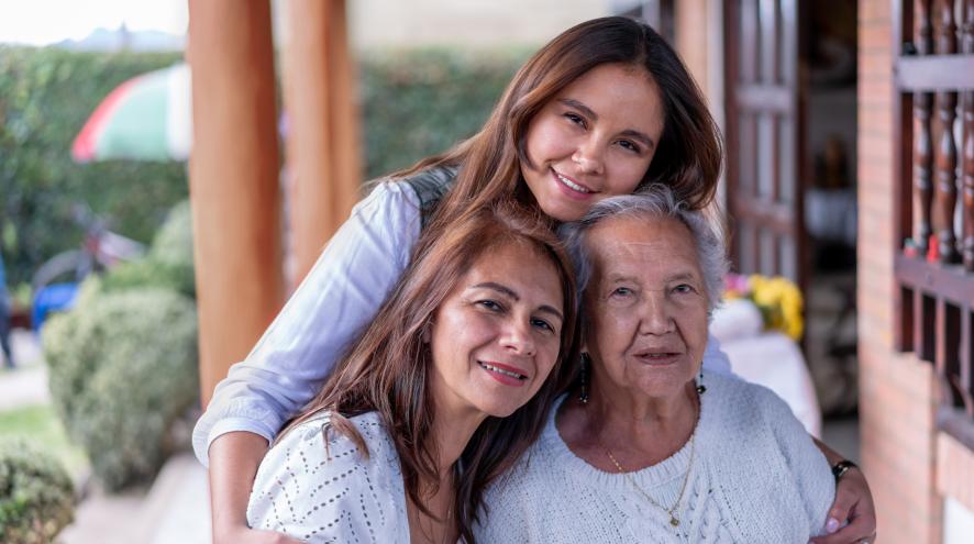 A young woman, midlife woman and elderly woman embrace