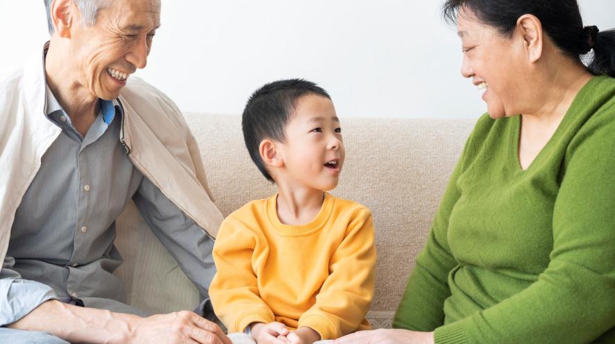 Two adults sitting on couch with a young boy, smiling and talking