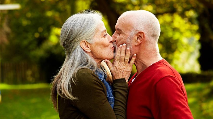 Older woman kissing older man outdoors