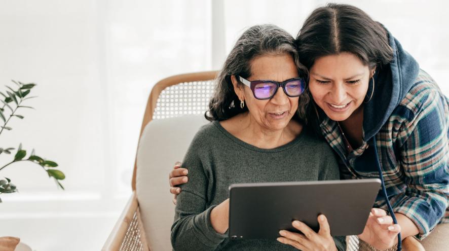 Older woman and younger woman looking together at tablet and learning
