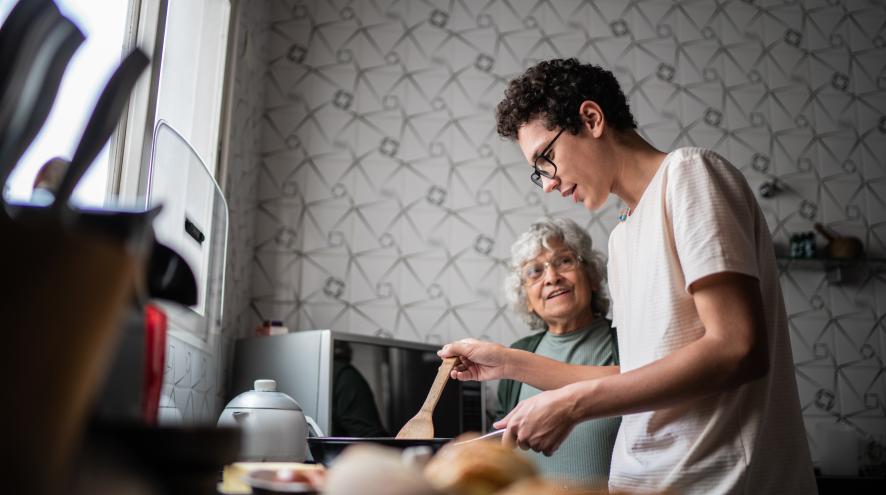 Teenage boy cooking with his grandmother